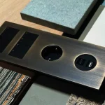 Brass finish multi-outlet panel with two USB ports and circular sockets, surrounded by sample materials.