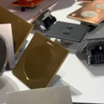 Close-up of metallic electrical switch faces and recessed lighting components in gold, copper, and silver tones.