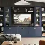 Living room with a dark blue built-in media unit and shelves around a wall-mounted TV, neatly concealing sockets; stylish décor and a cosy seating area. how to hide plug sockets in living room