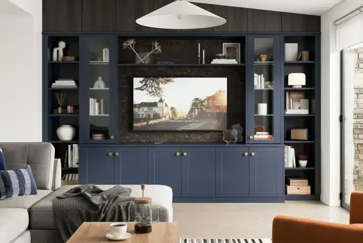 Living room with a dark blue built-in media unit and shelves around a wall-mounted TV, neatly concealing sockets; stylish décor and a cosy seating area. how to hide plug sockets in living room