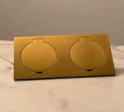 Polished brass double light switch cover with two circular cutouts, resting on a marble surface. Polished brass double light switch cover with two circular cutouts, resting on a marble surface.